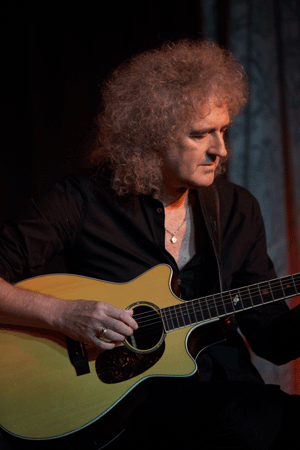 queen guitarist playing acoustic guitar