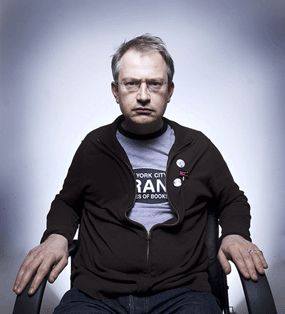 robin ince sitting in chair glasses looking angry